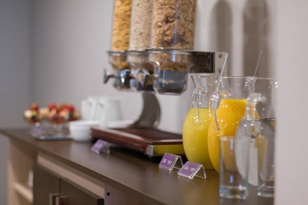 Una barra de desayuno con una máquina de café, una exhibición de frutas y un dispensador de agua.