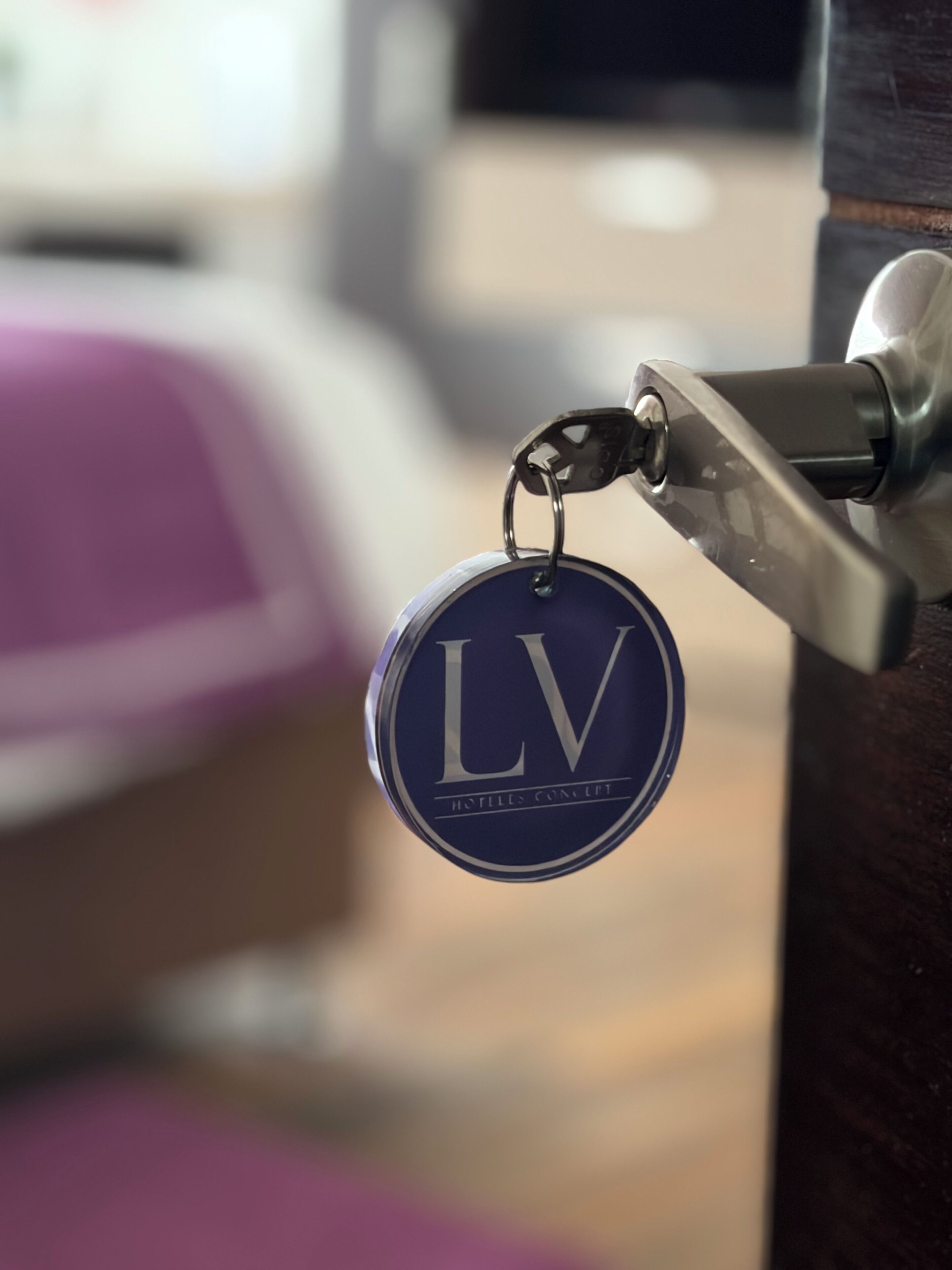 Um chaveiro com as letras 'LV' e a inscrição 'HOTEL CONCEPT'.