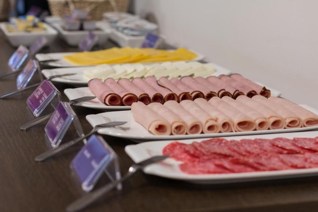 Mesa de buffet com diversos alimentos, incluindo fatias de carne e queijos.