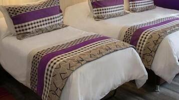 Habitación de hotel con dos camas, cada una con ropa de cama estampada y cabeceros.