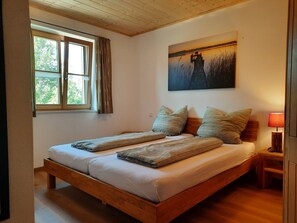 Ein Doppelbett mit Holzrahmen, zwei Kissen, eine Decke, ein Nachttisch mit Lampe und ein Bild an der Wand.