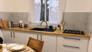Una cuina compacta amb rentatge, fogó i taulell de fusta.
