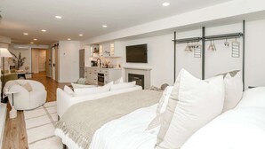 A bedroom with a large bed, a TV, a fireplace, and a walk-in closet. - Apt Near Yale|Walkable&Cozy/ for Connection & Rest (New Haven)