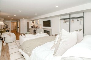 Ein Schlafzimmer mit einem großen Bett, einem Fernseher, einem Kamin und einem begehbaren Kleiderschrank.