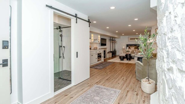 A modern interior with a sliding door leading to a shower, a kitchen area, and a seating space with a plant. - Apt Near Yale|Walkable&Cozy/ for Connection & Rest (New Haven)