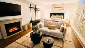 A modern living room with a fireplace, sofa, coffee table, and a television. - Apt Near Yale|Walkable&Cozy/ for Connection & Rest (New Haven)