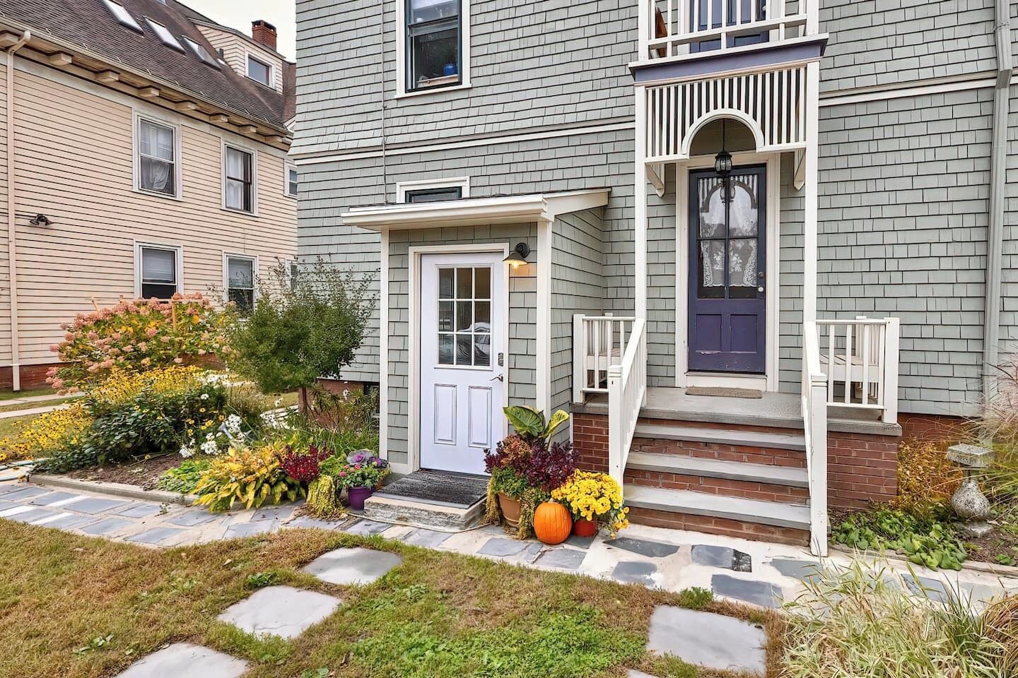A two-story house with a front porch, a white door, and a blue front door.