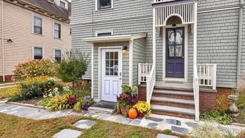A two-story house with a front porch, a white door, and a blue front door.