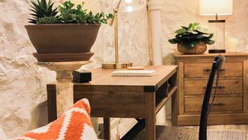 A cozy room with a wooden desk, a chair, a lamp, and a potted plant.