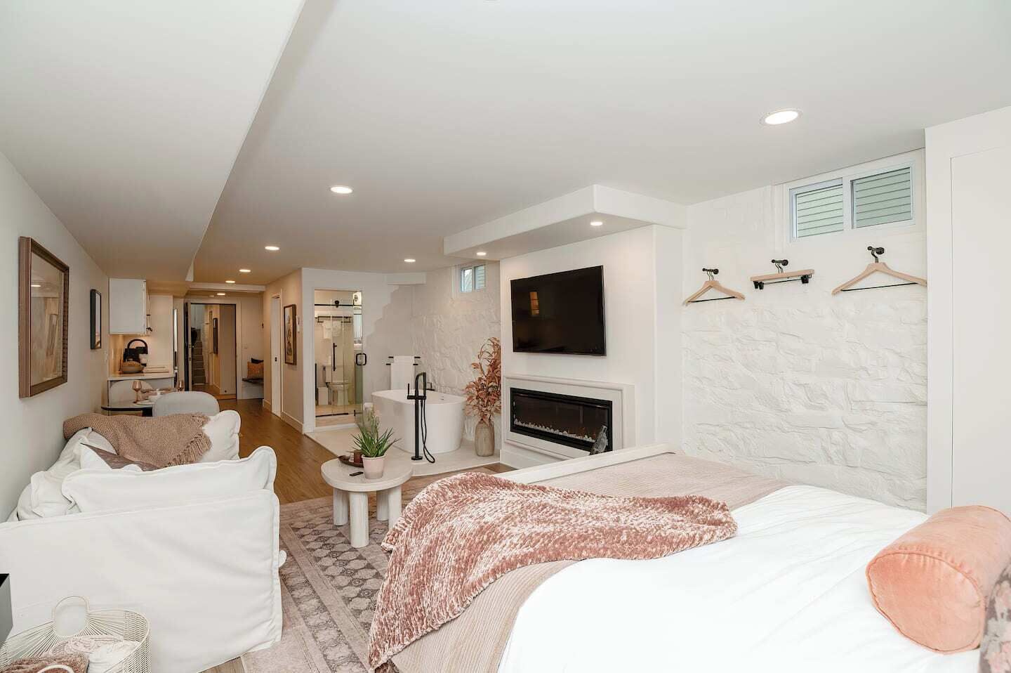 Ein modernes Hotelzimmer mit Bett, Sitzecke, Fernseher, Kamin und einem Badezimmer mit Dusche und Toilette.