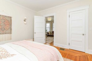 Ein Schlafzimmer mit einem Bett, einer Tür zu einem anderen Raum und einer Wandleuchte.