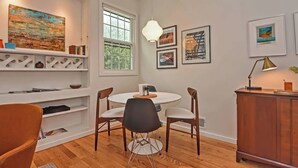 A dining area with a round table, chairs, a pendant light, and artwork on the walls.