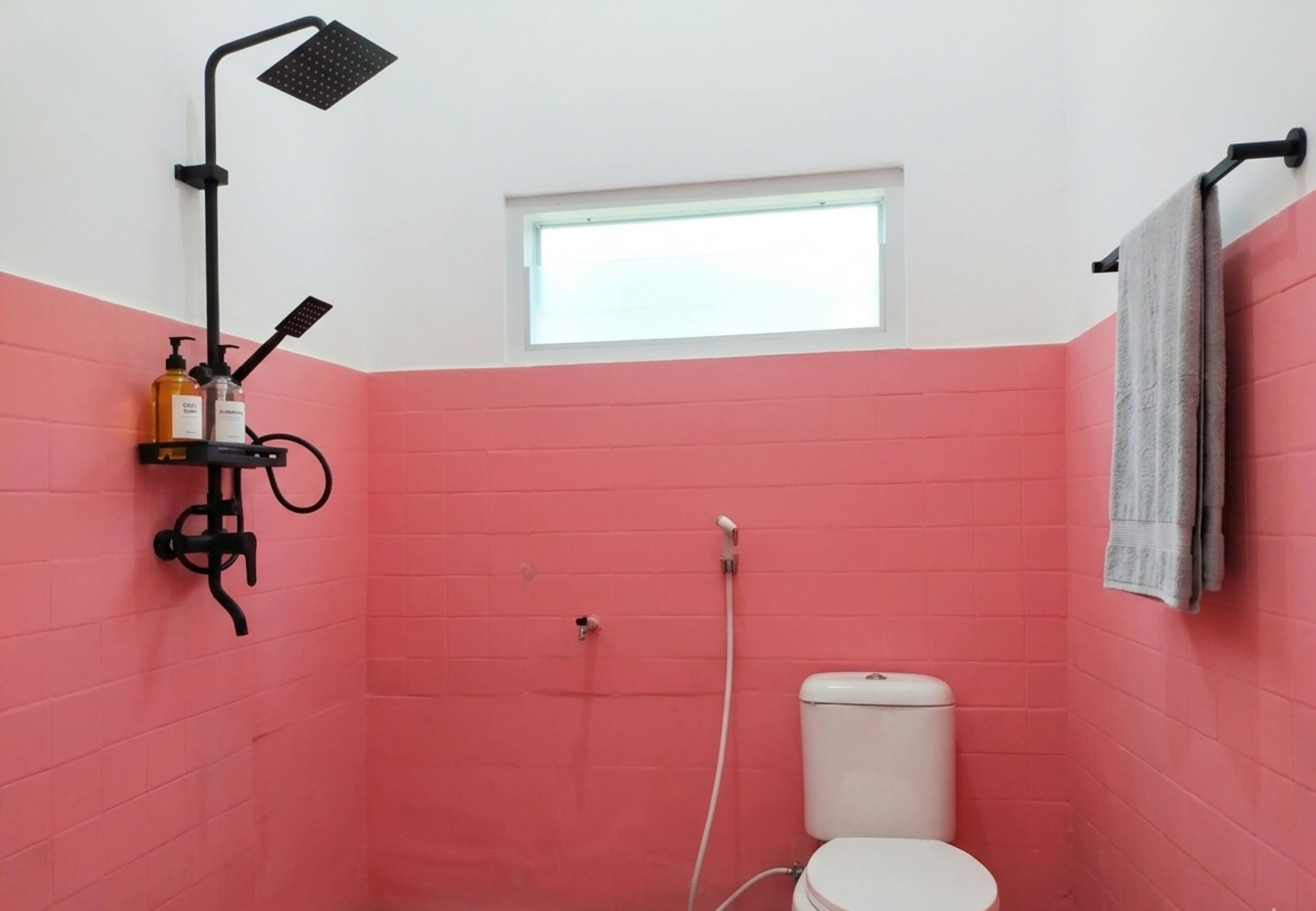 A small bathroom with a shower, toilet, and a window.