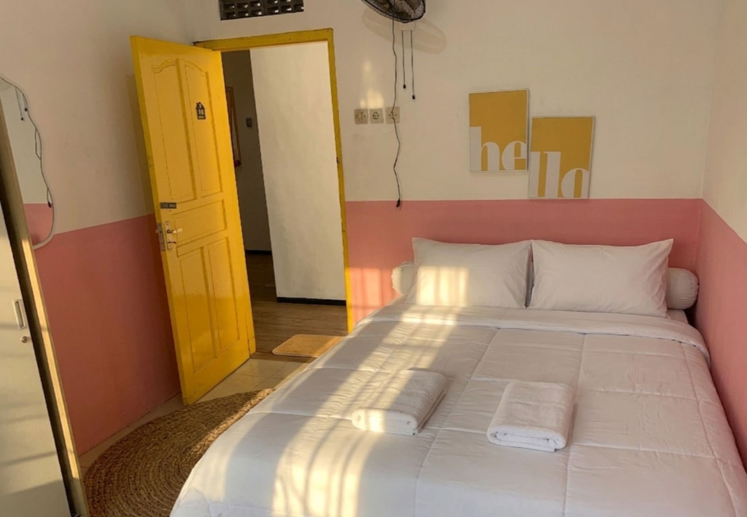 Un dormitorio con una cama, una puerta y una pared con un cartel que dice 'hello'.