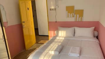 A bedroom with a bed, a door, and a wall with a 'hello' sign.