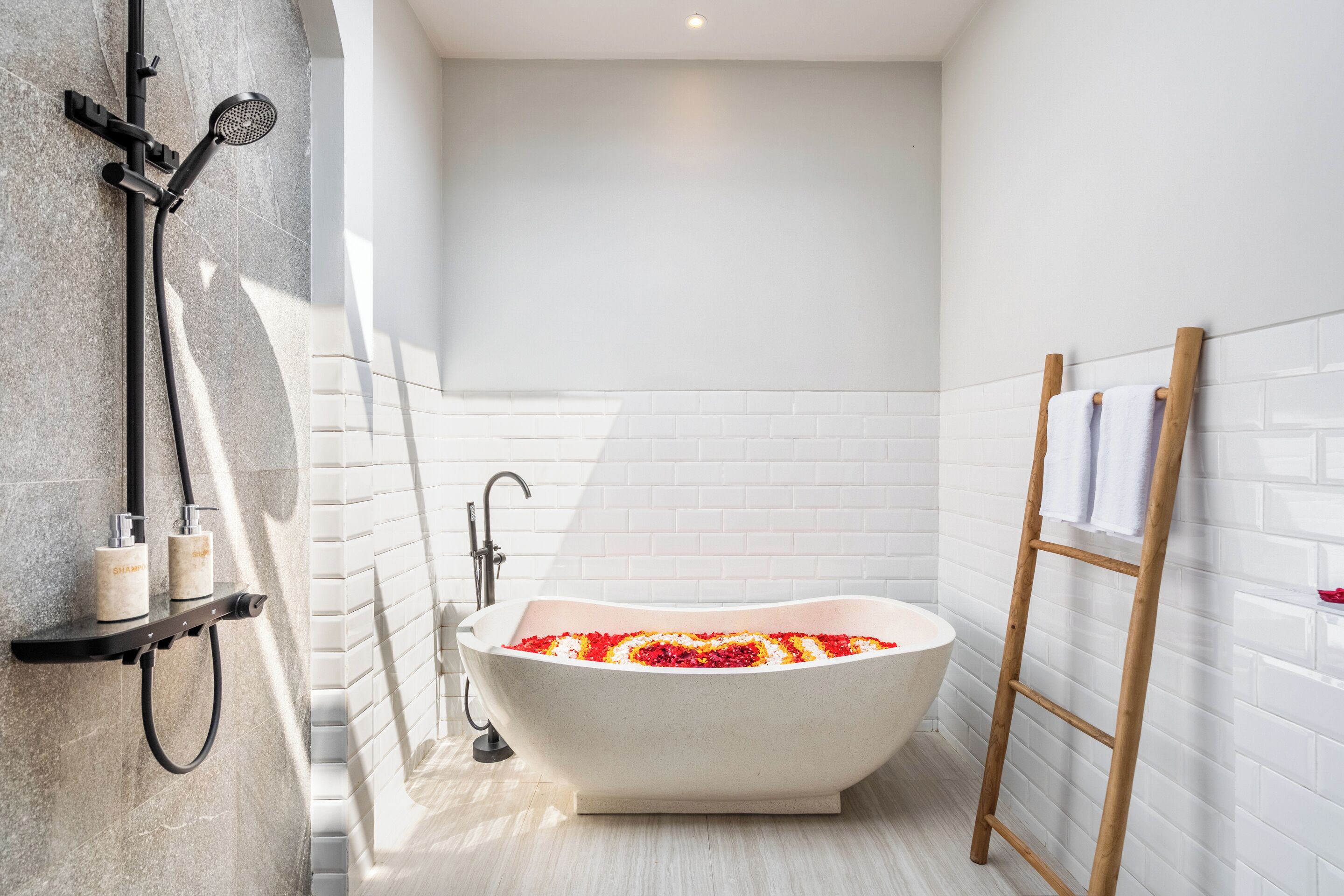 Un baño moderno con una bañera independiente, un cabezal de ducha y una escalera de madera.