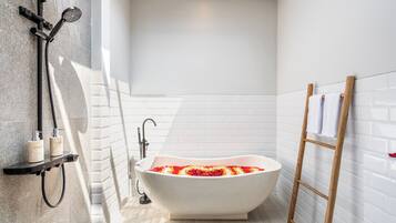 Un baño moderno con una bañera independiente, un cabezal de ducha y una escalera de madera.