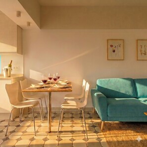 Ein Essbereich mit einem Tisch für vier Personen, einem blaugrünen Sofa und einem hexagonal gemusterten Boden.
