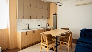 Uma cozinha moderna com armários de madeira, bancada de mármore, pia e um espaço de refeições com mesa e cadeiras.