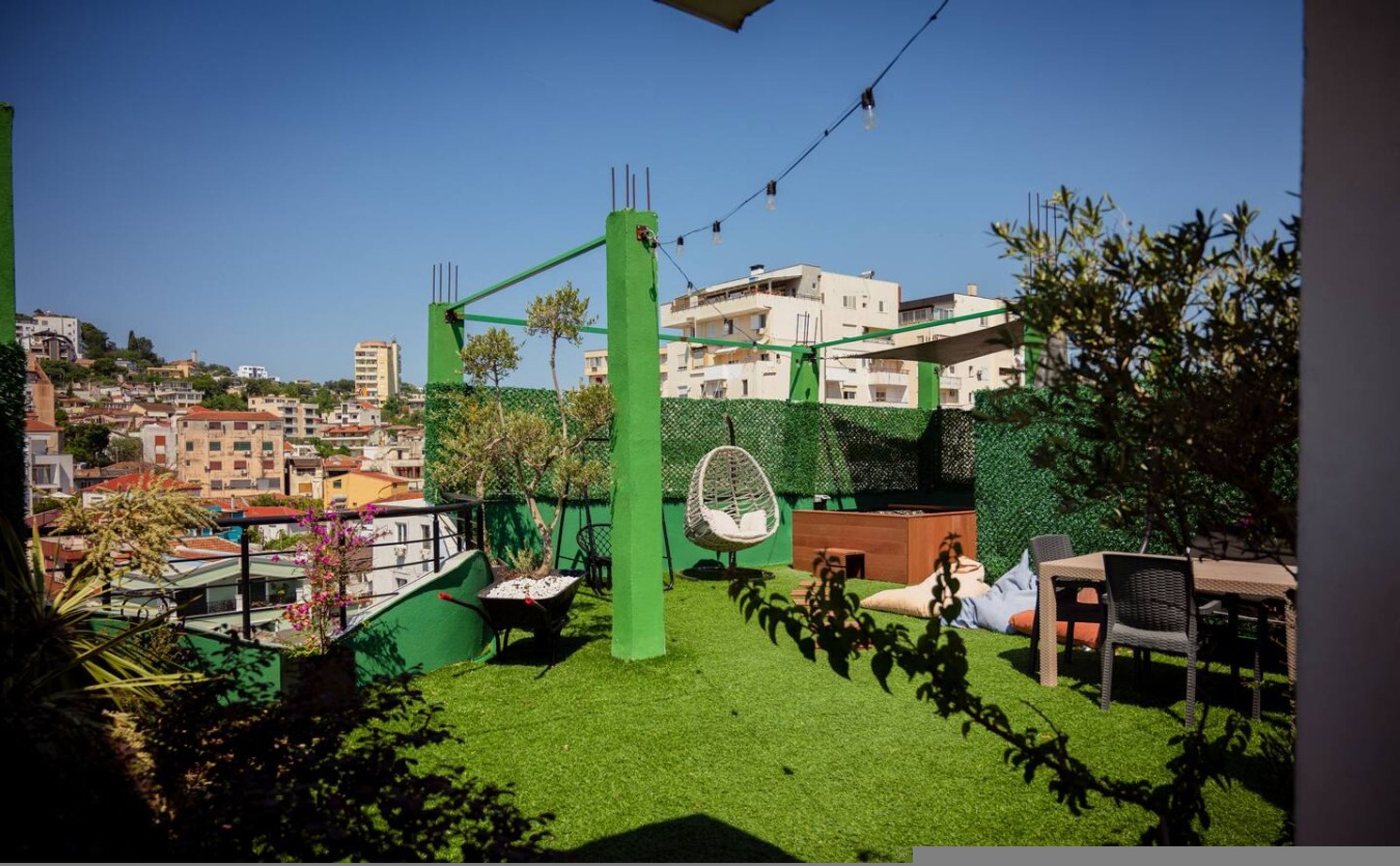 A rooftop garden with a swing chair, a wheelbarrow, and a seating area.