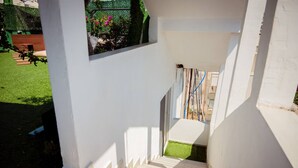 Uma escadaria leva a uma varanda com vista para um jardim e uma cerca.