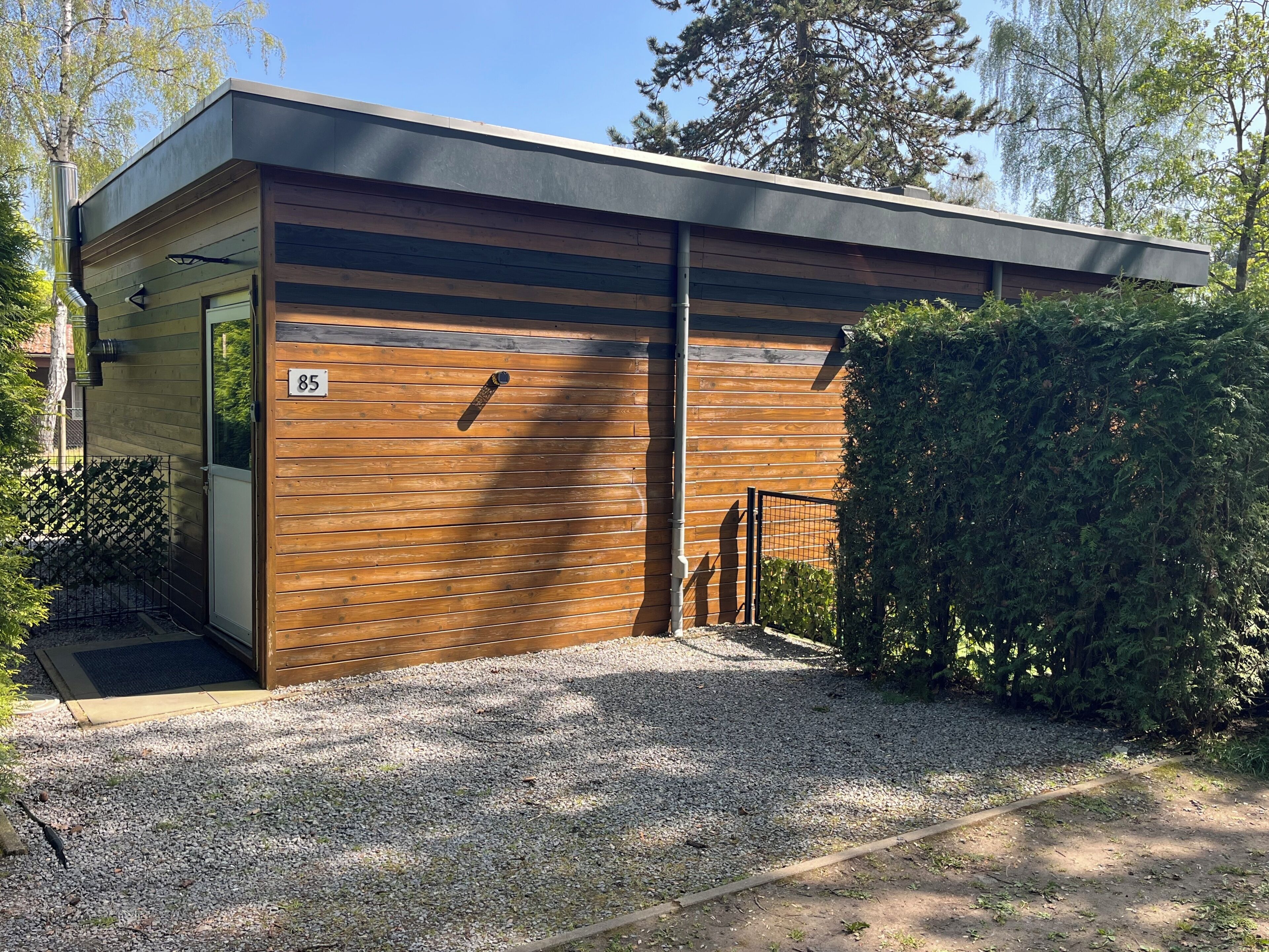 Ein modernes Gebäude mit Holzfassade, Metall-Dach und einem Schotterweg.