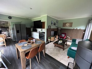 A compact living space with a dining area, kitchenette, and a seating area with a TV and red chair. - Cozy little chalet for a family of up to 4 people and their little rascals (Lanaken)