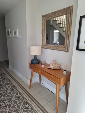 Een hal met een houten console tafel, een lamp, een decoratief object en een spiegel.