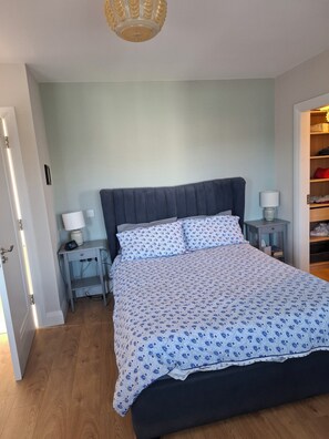 Ein Schlafzimmer mit einem Bett, zwei Nachttischen, einem Kleiderschrank und einer Tür.