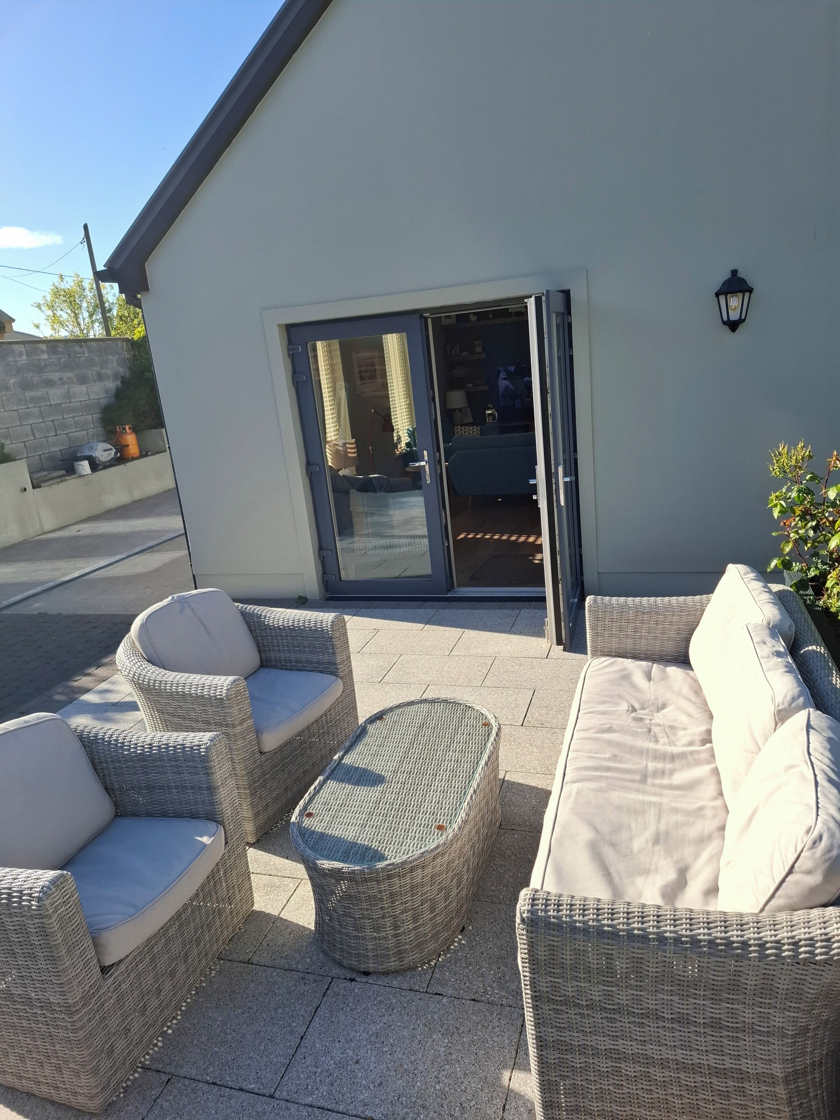 An outdoor seating area with wicker furniture and a sliding glass door leading to an interior space.