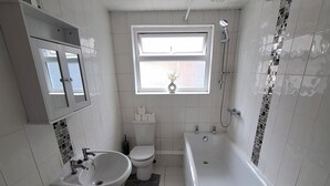 A modern bathroom with a bathtub, a sink, and a toilet. - Alice Place (Sunderland)