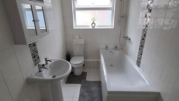 A modern bathroom with a bathtub, a sink, and a toilet.