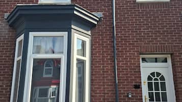 A brick house with a bay window, a white door, and a number plate.