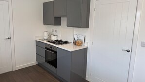 A compact kitchen with grey cabinets, a white countertop, a built-in oven, and a gas stove. - House Sleeps 6 With Parking and Garden (Liverpool)