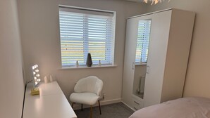 A bedroom with a vanity, a chair, a bed, and a wardrobe. - House Sleeps 6 With Parking and Garden (Liverpool)