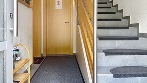 Una escala amb barana, una porta de fusta i un cartell de prohibició de fumar, i també un arxivador de revistes.