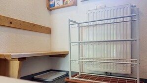 Habitació amb un radiador blanc, una prateleira de fusta i un escuraprius metàl·lic.