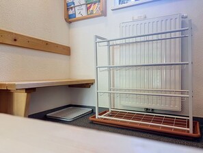 Ein Zimmer mit einem weißen Heizkörper, einem Holzbodenregal und einem Wäscheständer aus Metall.