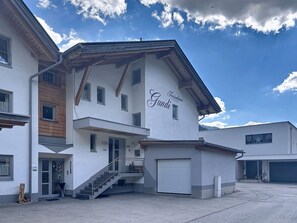 Ein modernes Gebäude mit einem Schild, auf dem 'Ferienhaus Gundi' steht, und einer Treppe, die zum Eingang führt.