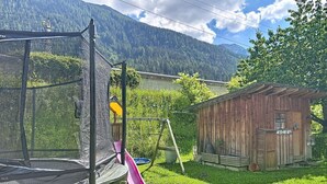 Un pati amb un trampolí, un joc de balanceig i una caseta de fusta.
