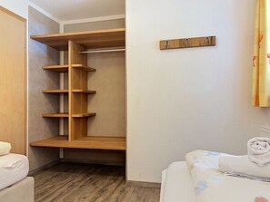 Een inloopkast met houten planken en een kledingroede.