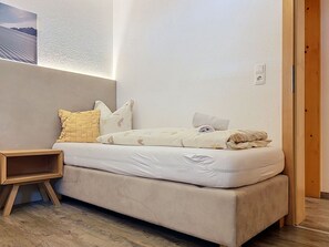 Een slaapkamer met een bed, nachtkastje en een wandlamp.