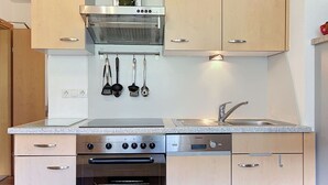 Eine moderne Küche mit Edelstahlgeräten, Holzschränken und einem eingebauten Backofen.