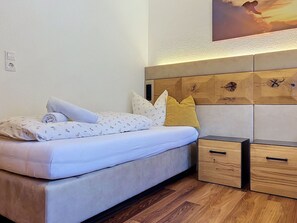 Ein Schlafzimmer mit einem Bett, Kissen, einem Nachttisch und einem Holz-Kopfteil.
