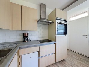 Uma cozinha com forno embutido, cafeteira e torradeira.