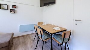 Ein kleiner Essbereich mit Tisch, Stühlen und einem an der Wand befestigten Fernseher.