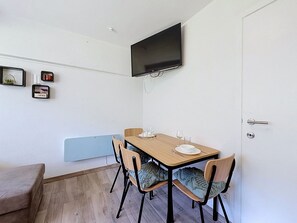 Ett litet matområde med ett bord, stolar och en tv som är monterad på väggen.