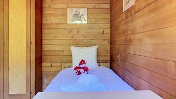 Quarto de cabana de madeira com uma cama, uma porta e um quadro na parede.