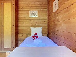 Una habitación de cabaña de madera con una cama, una puerta y un cuadro enmarcado en la pared.