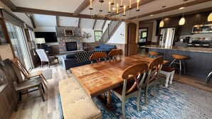 A spacious dining area with a large wooden table and chairs, a stone fireplace, and a kitchen with modern appliances. - Skye High Hideaway SLEEPS 18, 7 BRs, 4 baths, 2 living areas, a pool table, private hot tub, fire pit, and beach passes. (Lake Harmony)
